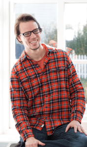 male employee sitting in a window and smiiling
