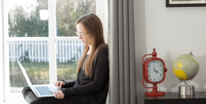 female employee sitting in a window and working on a laptop