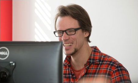 man laughing in front of a desktop computer