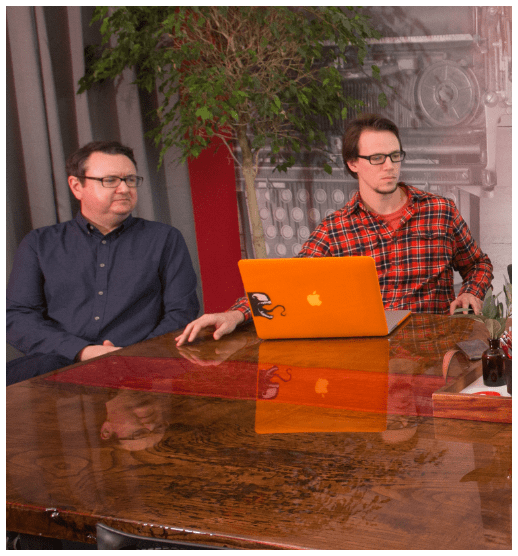 two men at a conference table with a laptop