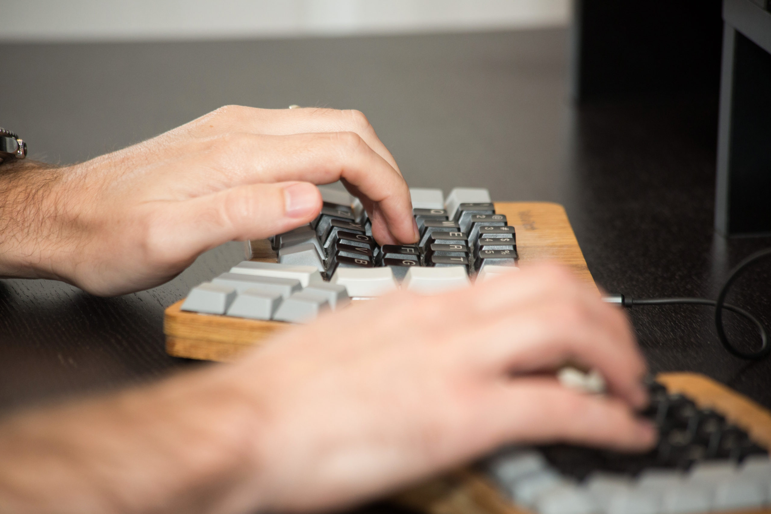 close up of hands typing on a wooden keyboard