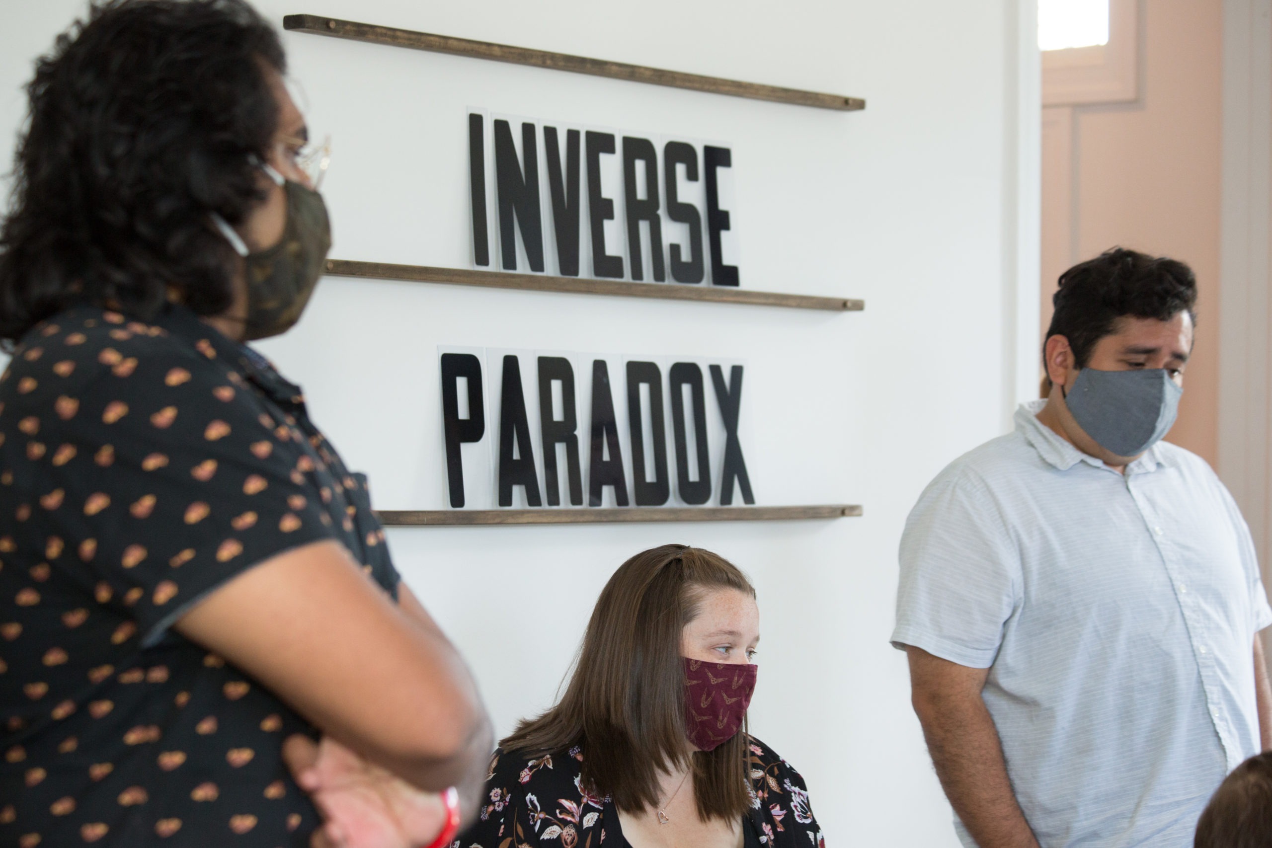 three employees in masks in front of an Inverse Paradox sign