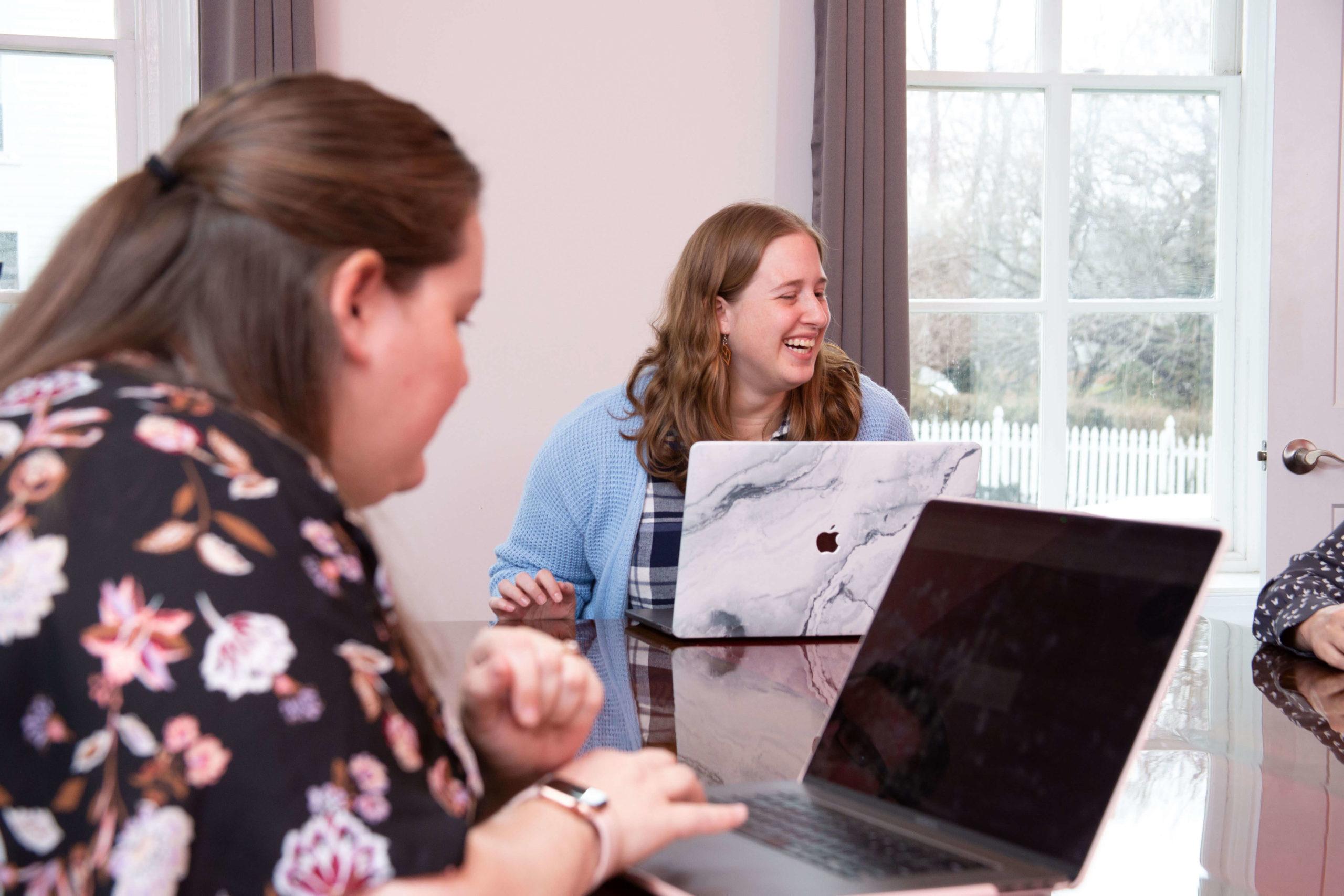 woman laughing in front of a laptop at a conference table