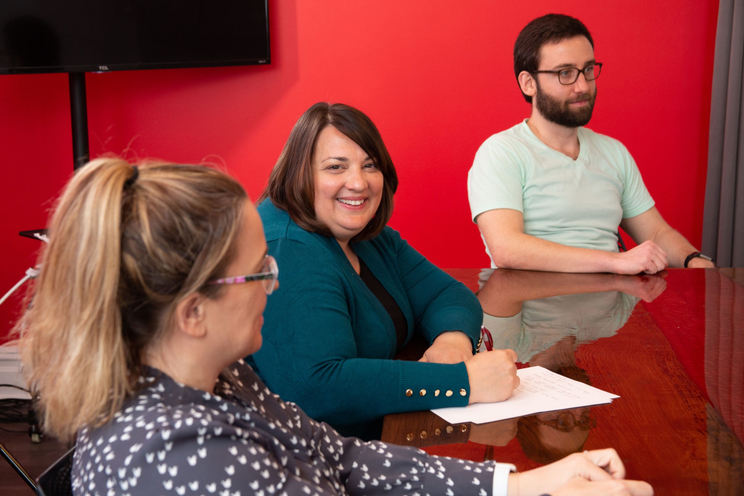 woman smiling and taking notes in a meeting