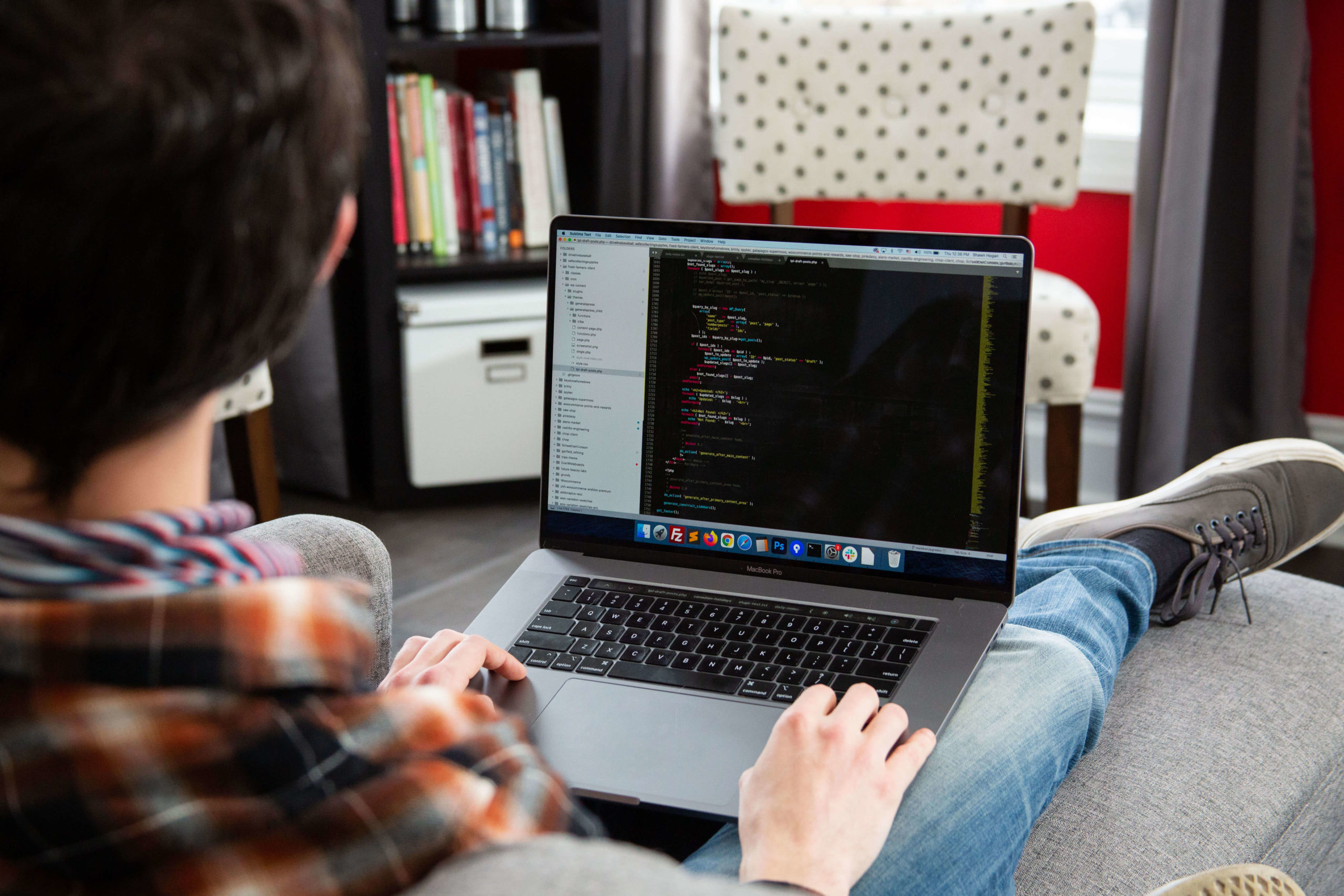 back of man writing code on a laptop