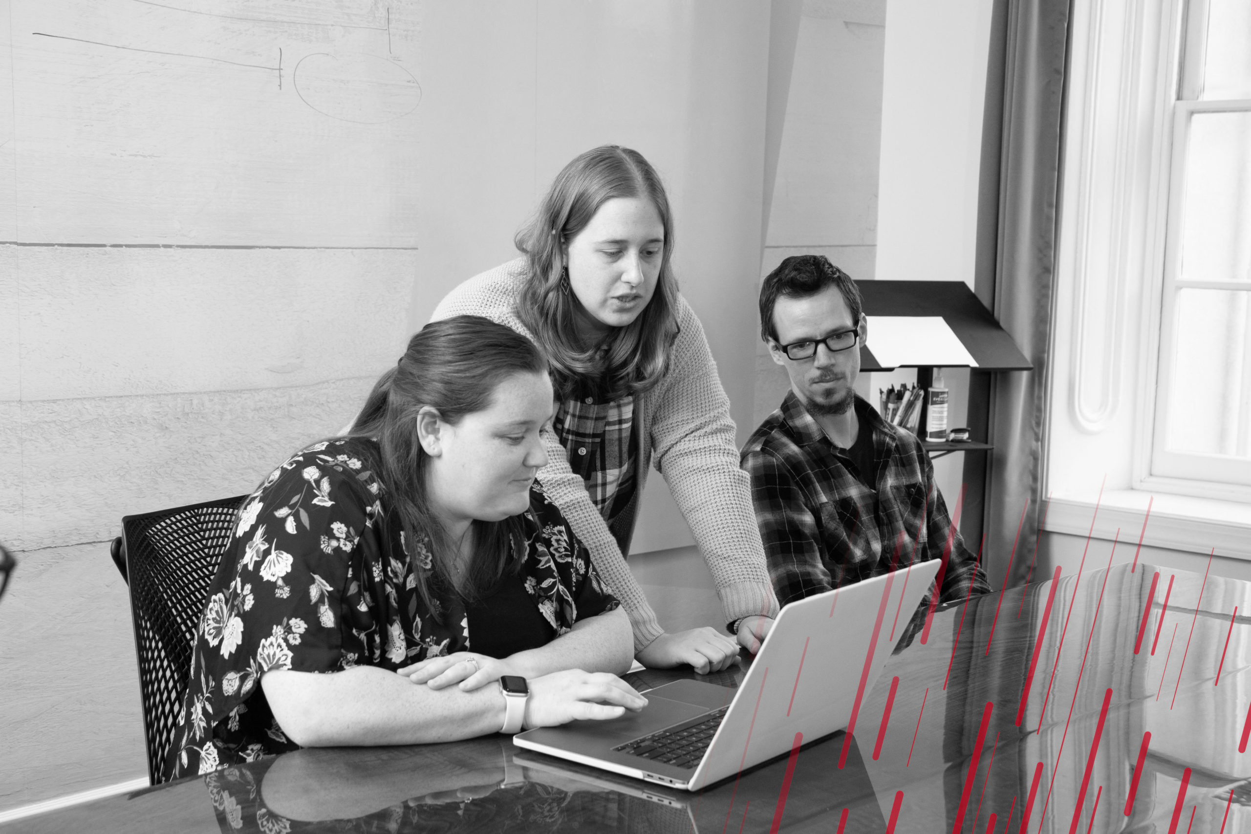 three employees looking at a laptop