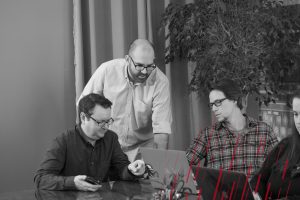 three men looking at a laptop