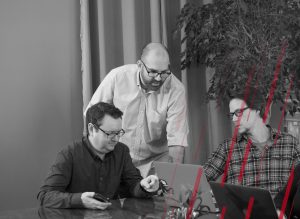three men looking at a laptop